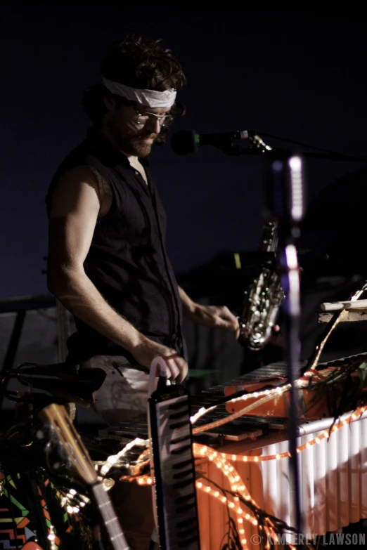 a man playing piano at night with a band