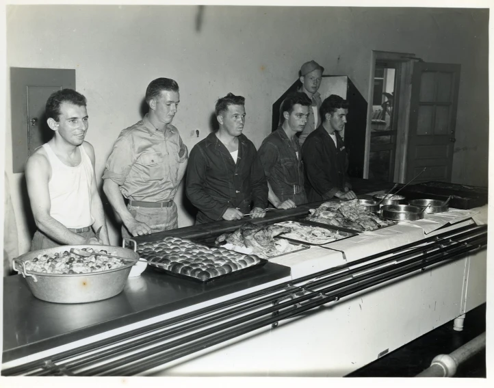 a black and white image of some men standing around some food