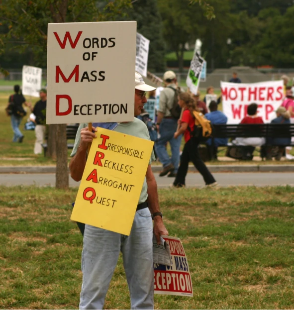 a man holding a sign that says words of mass deception