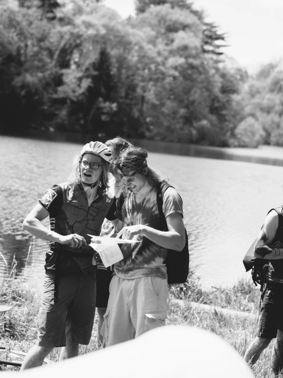 three men in camping gear standing next to a lake