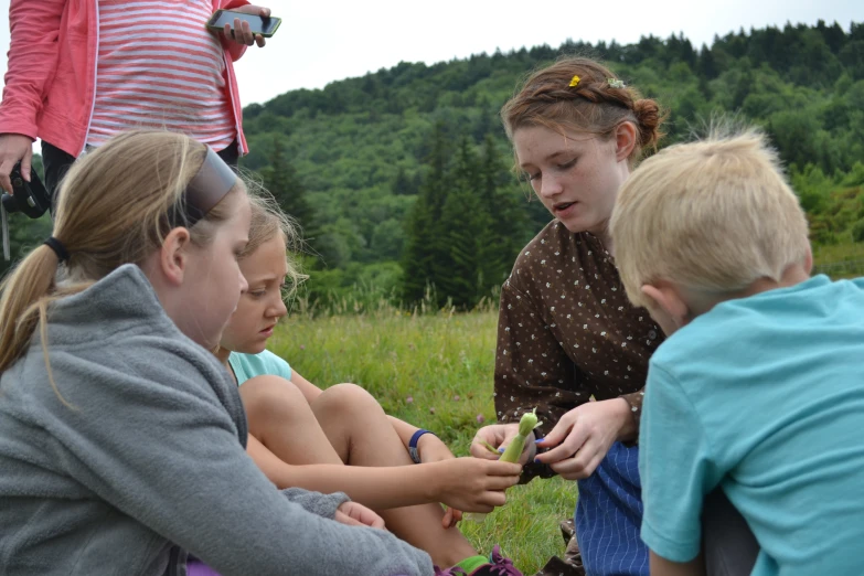 three girls are sitting down in the grass