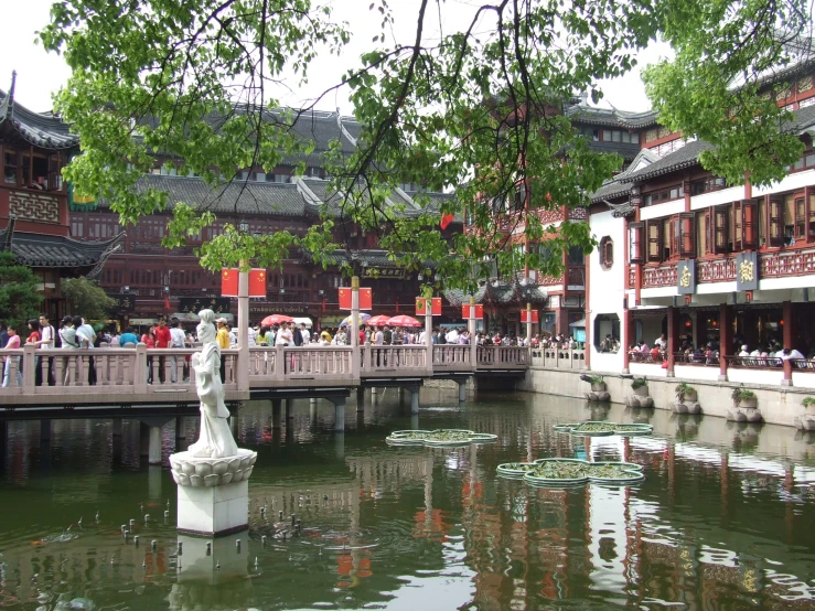 a river with a statue and a chinese town behind it