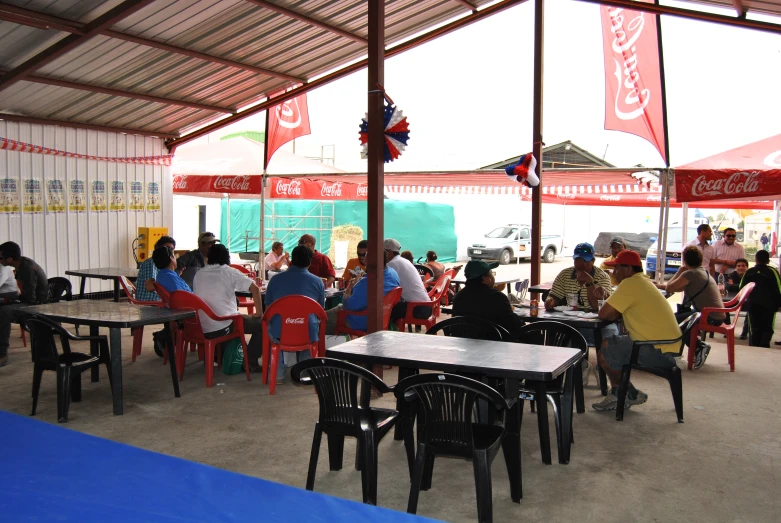 a group of people are under a tent with red and white table cloths