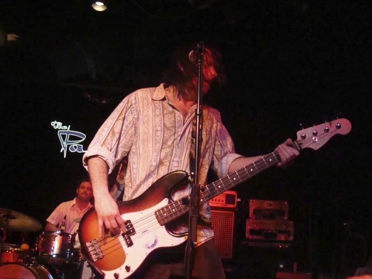 a man with a beard plays a bass guitar at the stage