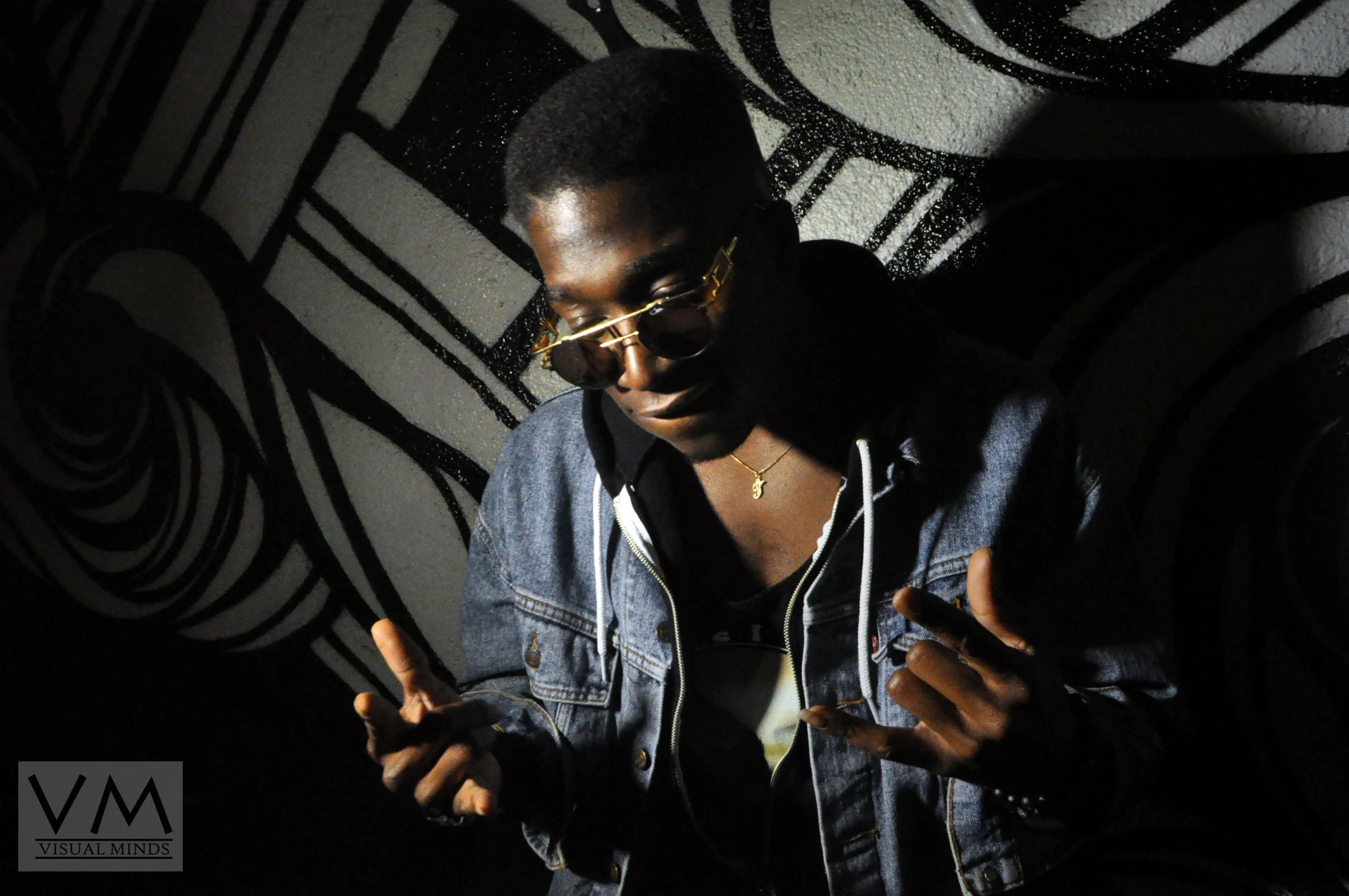 a person wearing a denim jacket and shades in a dark room