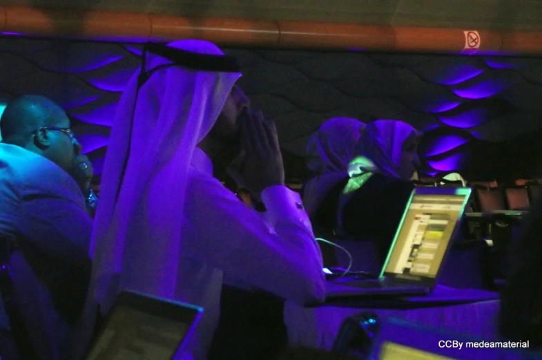 a couple people sitting in a booth with laptops