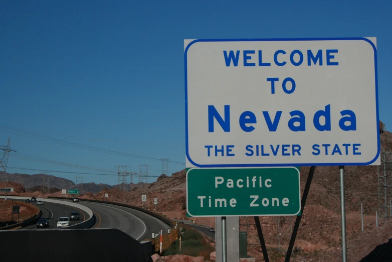 a welcome sign to nevada is next to the road