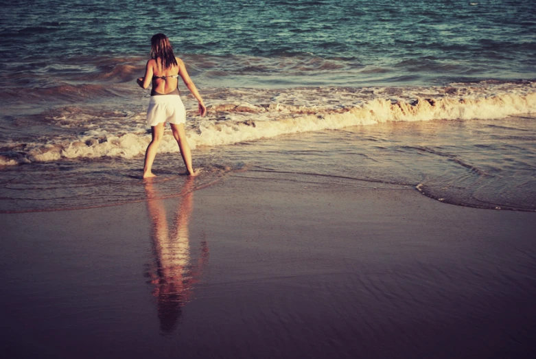 a girl standing in the surf with a frisbee