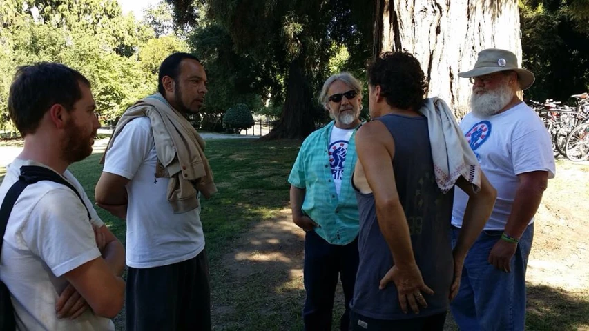 men are standing together in the park and talking