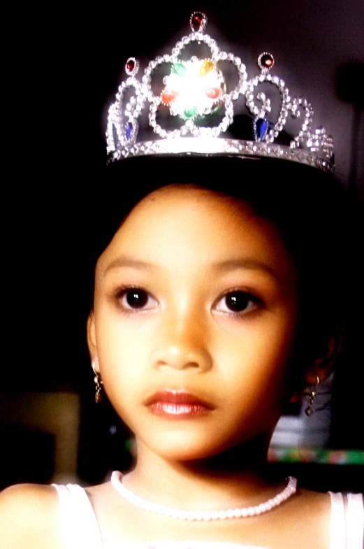 little girl wearing a tiara and pearl necklace