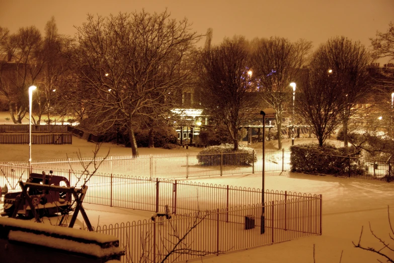 a snow covered park with a bench next to it