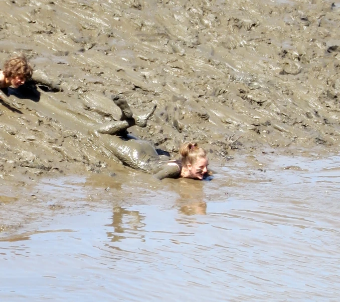 two s playing in the mud in the water