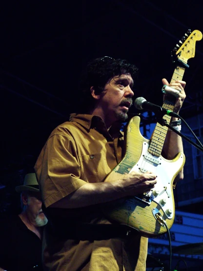 a man playing an electric guitar in front of a microphone