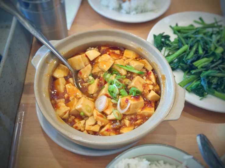 there is a bowl of food that includes tofu, asparagus, and onions