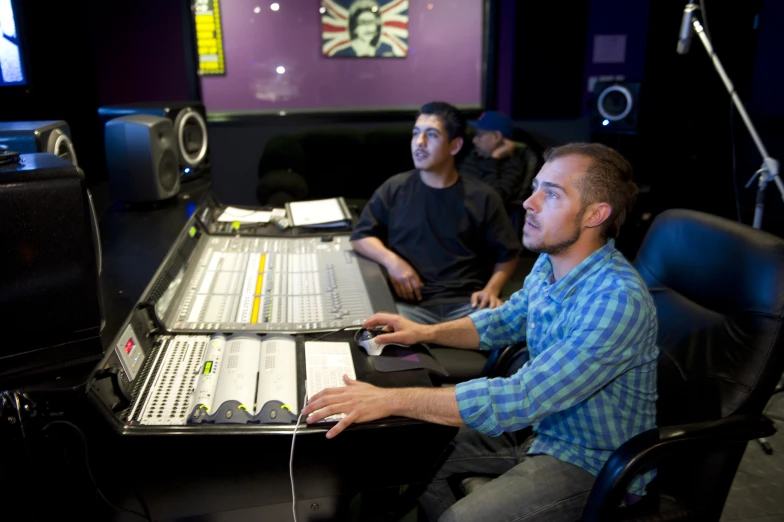 three men are sitting at a recording board