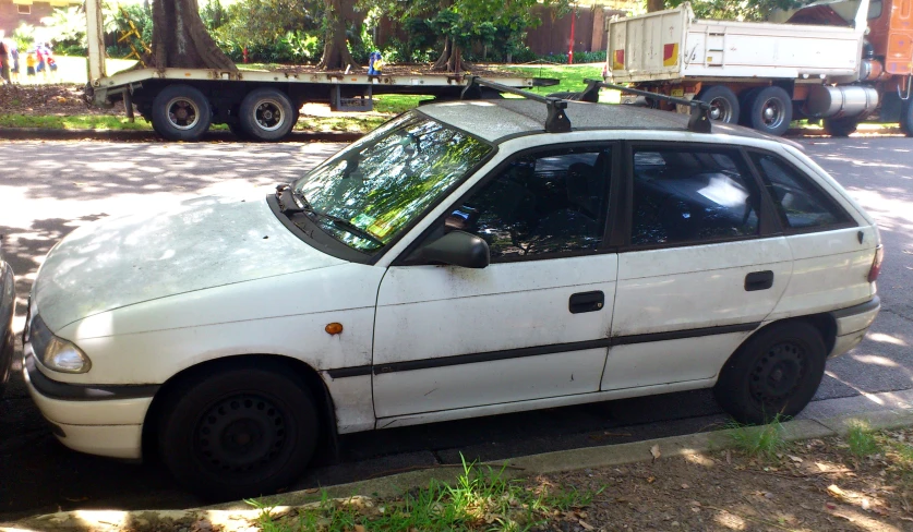 there is a small white car parked by the curb