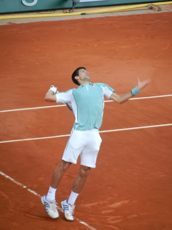 a man in a white shirt and white shorts playing tennis