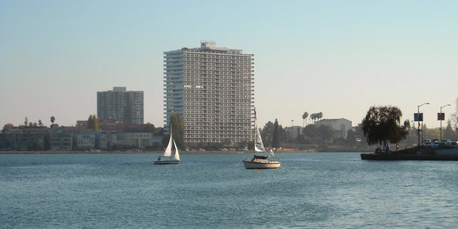 there is a small boat that can be seen on the lake in front of tall buildings