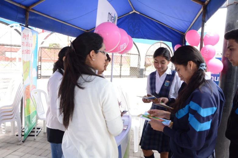 girls looking at paperwork under a blue tent