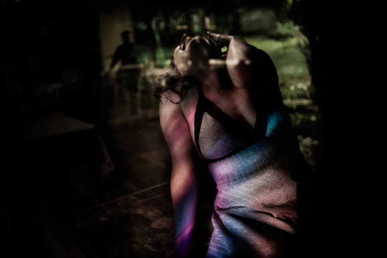 woman in brightly colored bodysuit resting her head on the glass wall