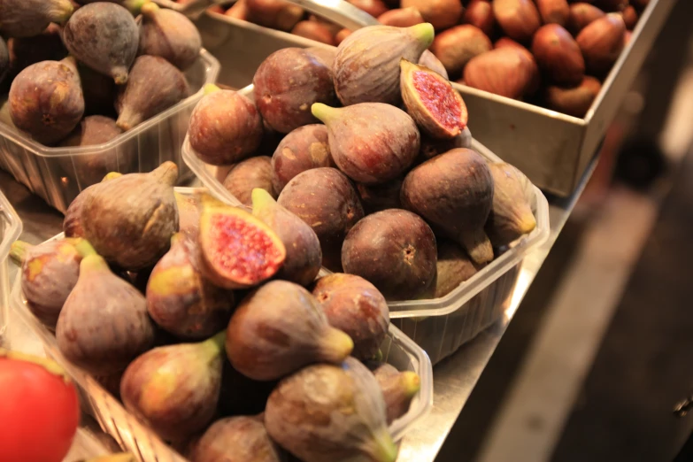 fruits sitting on display in plastic containers near tomatoes