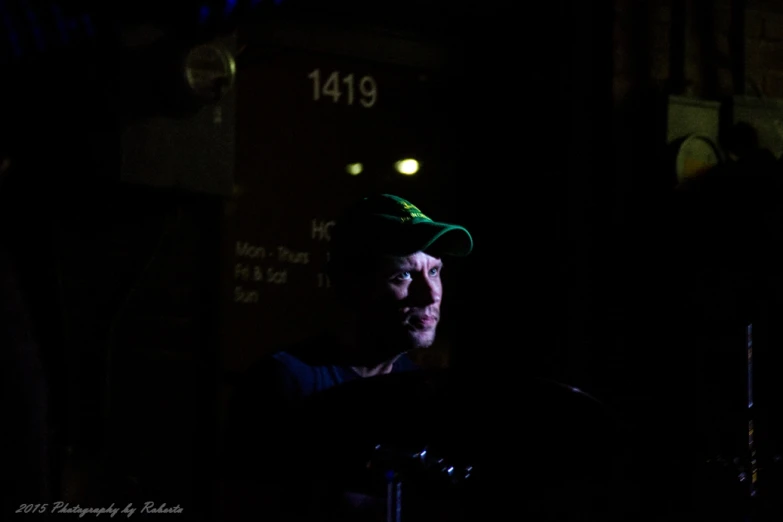 a man standing at night with a baseball cap on