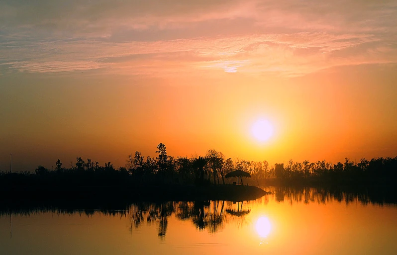 a boat on water with sun in sky behind it