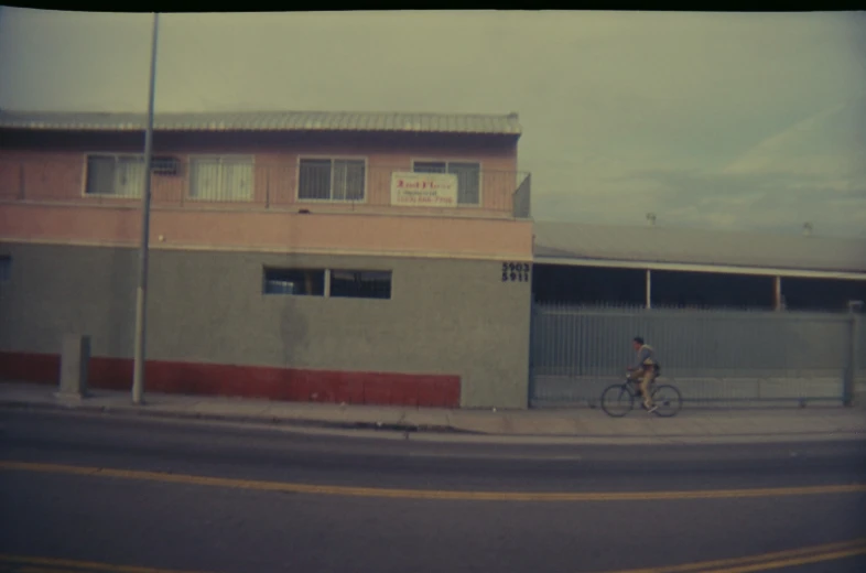 man riding bike on street past building in urban area