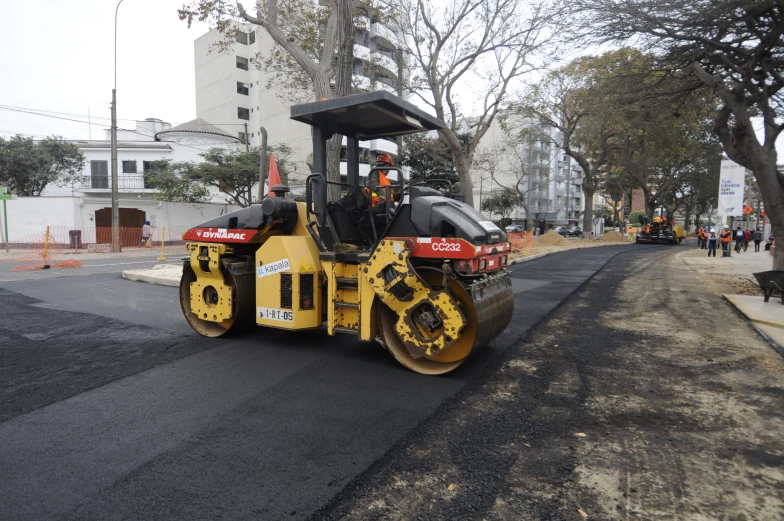 a yellow bulldozer with a red top driving down a street