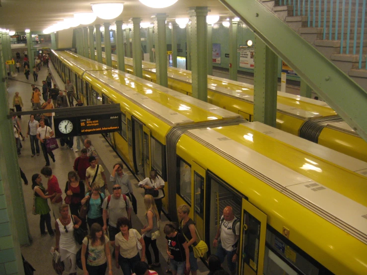 a group of people walking down a platform next to trains