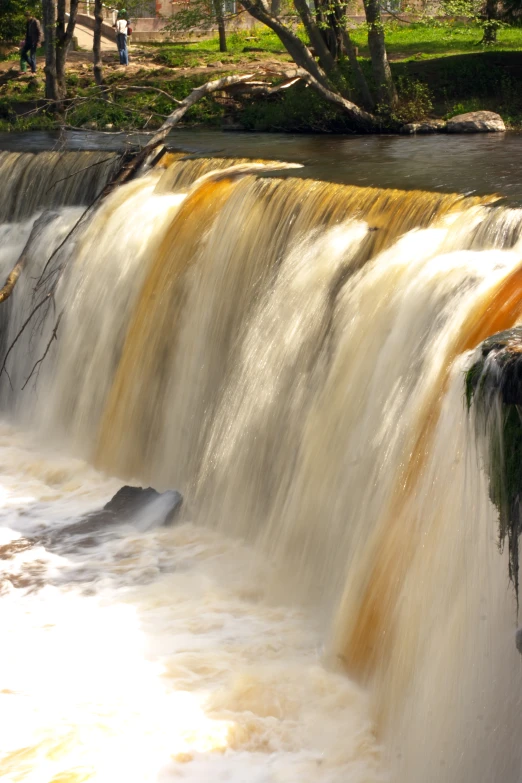 a waterfall made of rocks and water with yellow dye