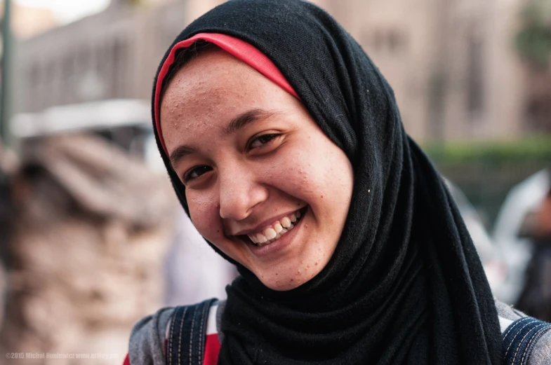 a woman wearing a head scarf smiling in front of a crowd