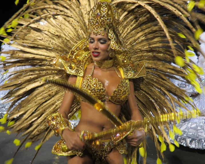 a woman wearing gold body art is shown performing