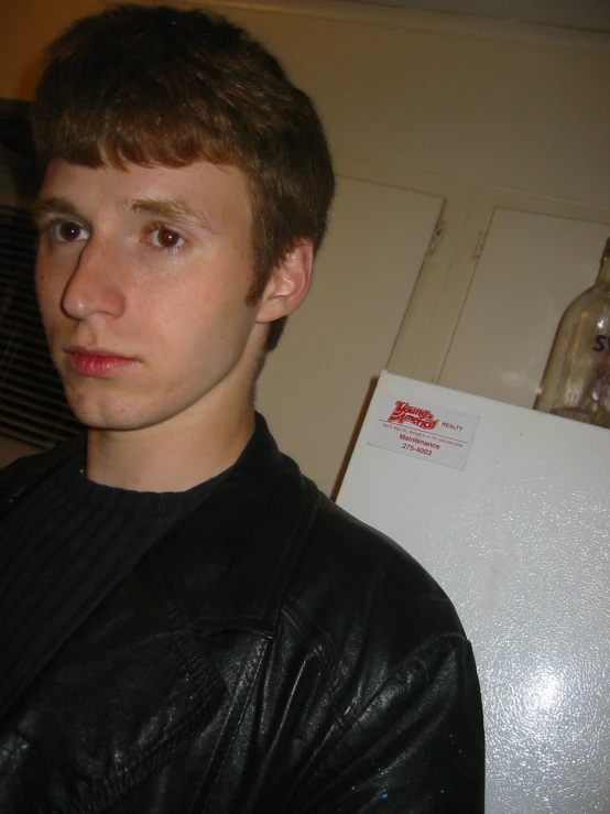 a young man is standing in front of a refrigerator