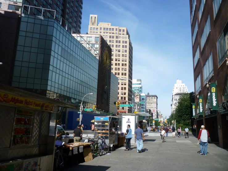 several people are walking on the sidewalk outside in a city