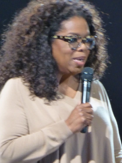 woman with glasses on speaking into a microphone