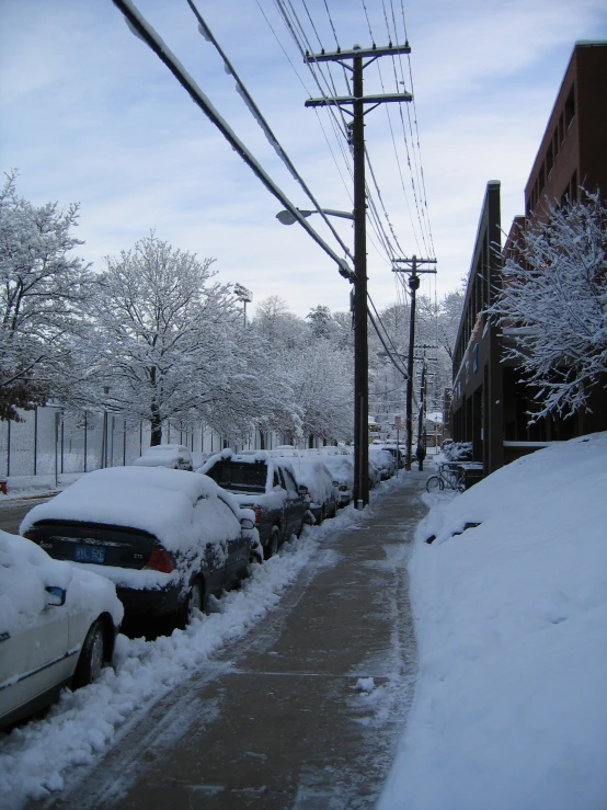 several cars parked along the side of a snow covered building