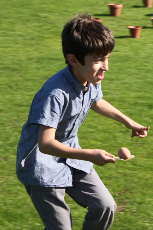 a boy holding two wooden balls and standing in front of the grass