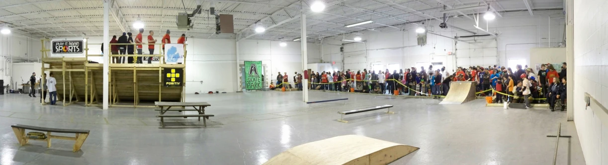 a crowd of people and skateboards inside a large building