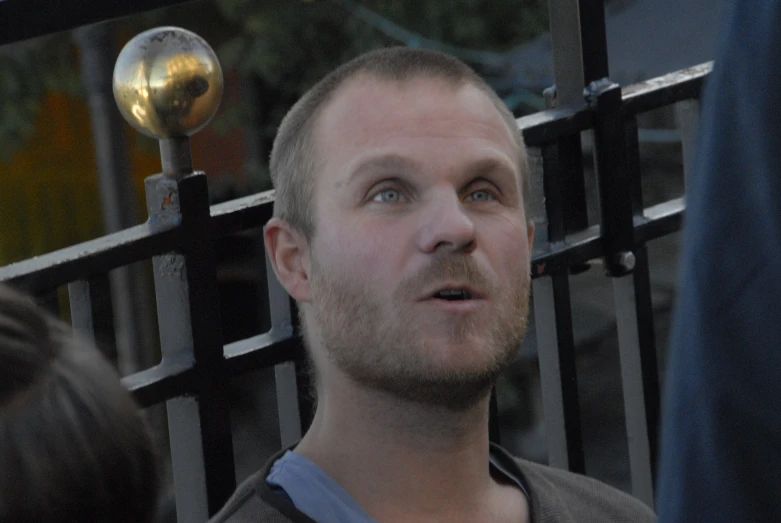 man looking up while standing in front of gate