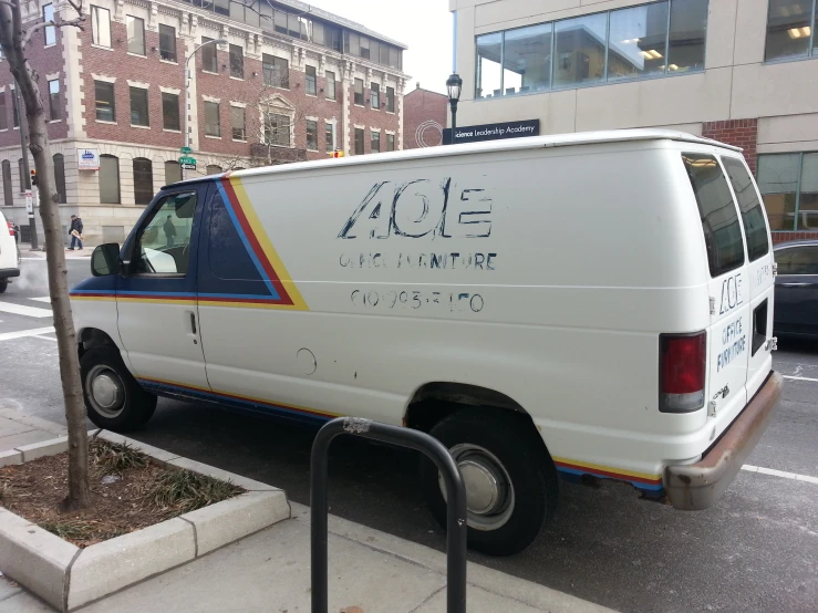 an white van parked on the side of a street next to a pole