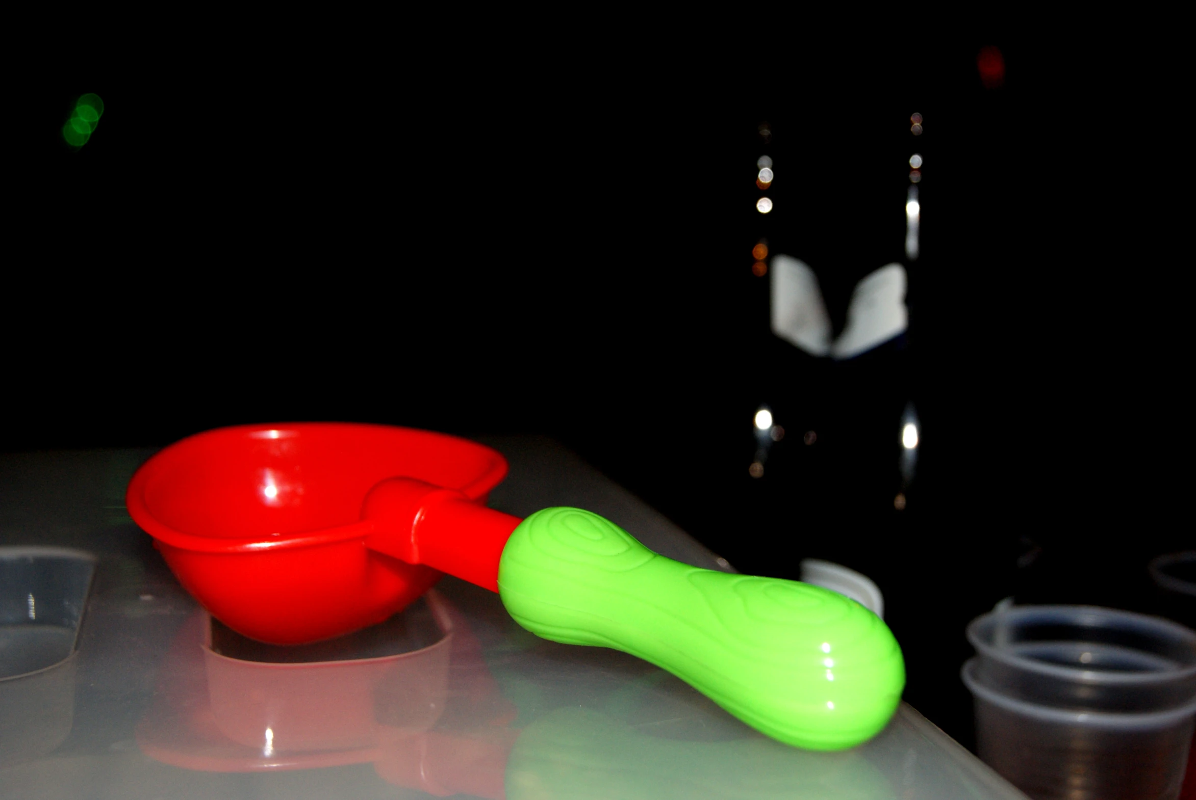 an orange bowl and green spoon on top of a table