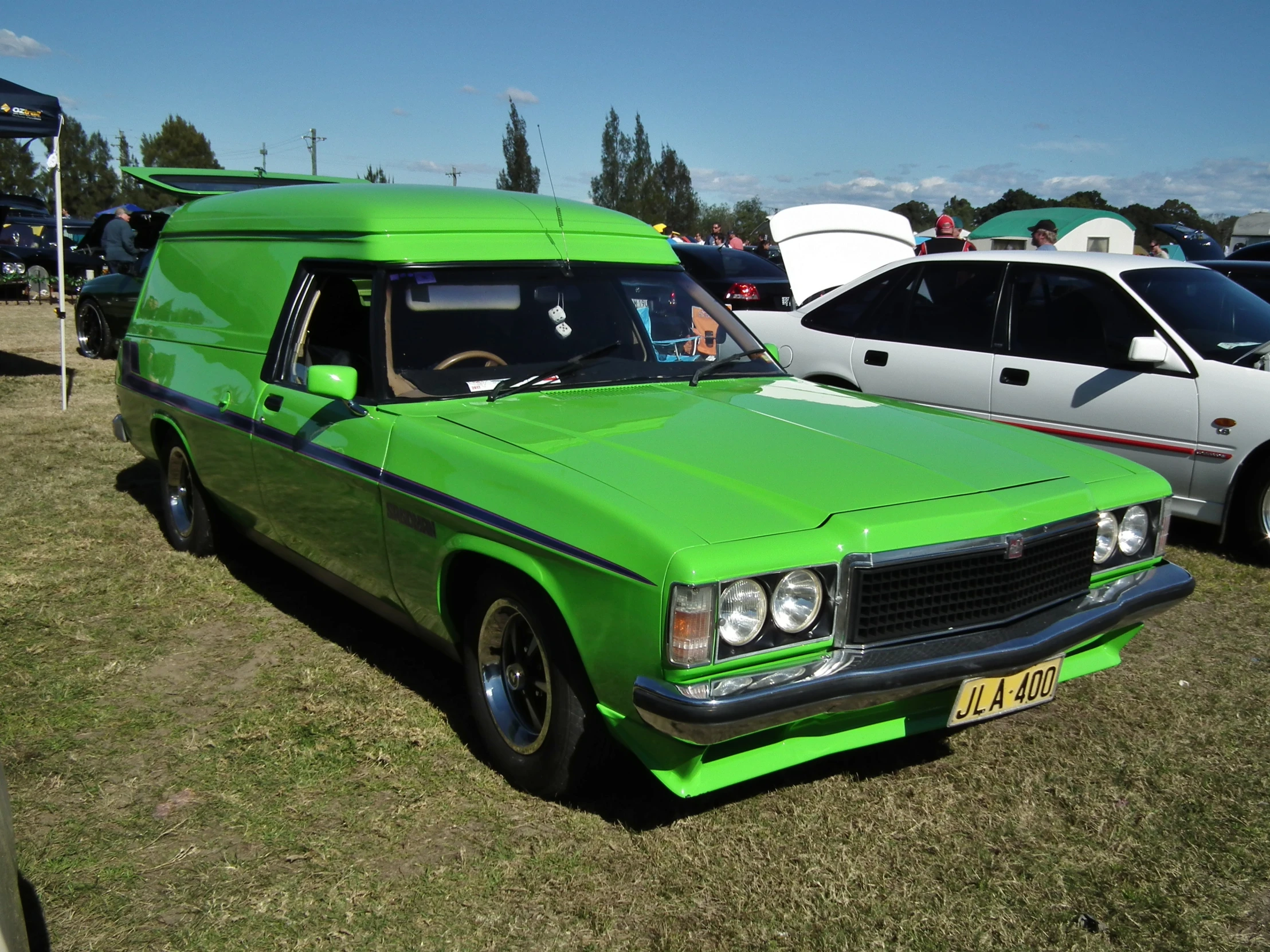 a green station wagon parked next to an old white van