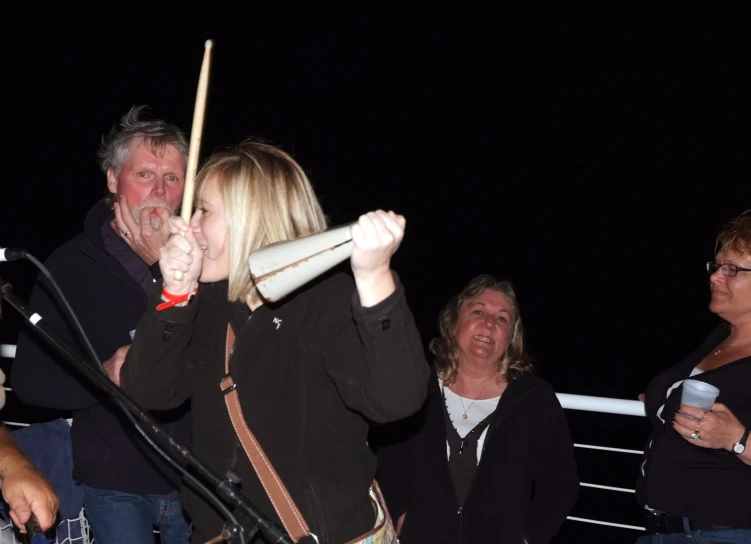 people watch as woman sings in a baseball bat