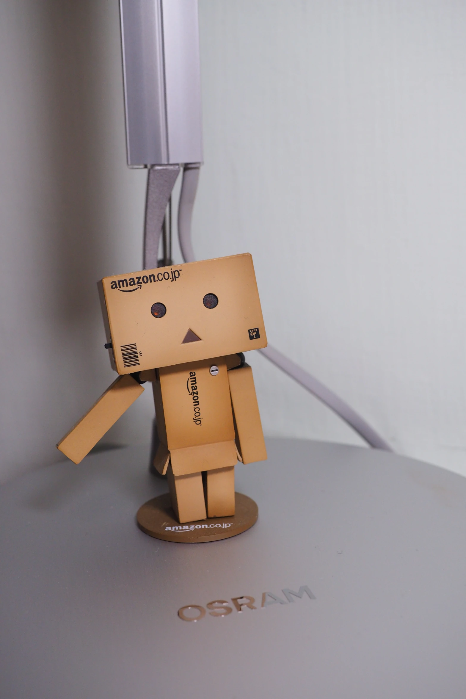 a small cardboard doll sitting on a counter next to a phone