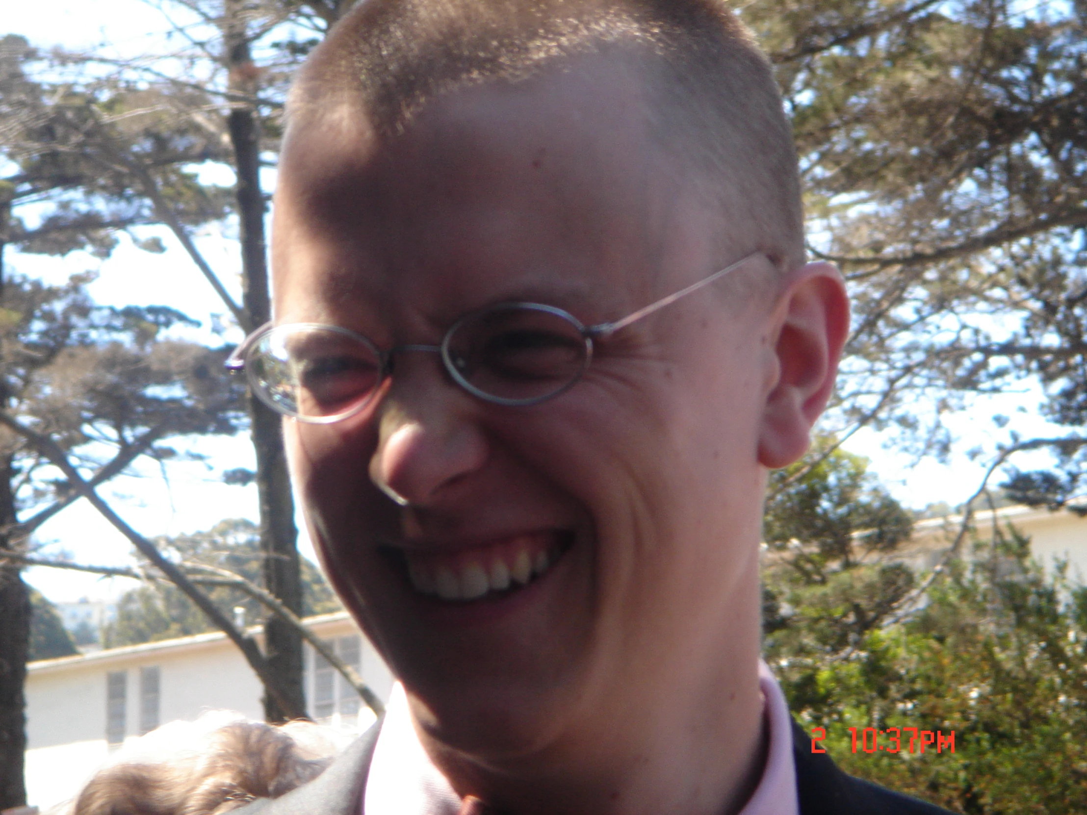 a man is smiling for the camera with trees in the background