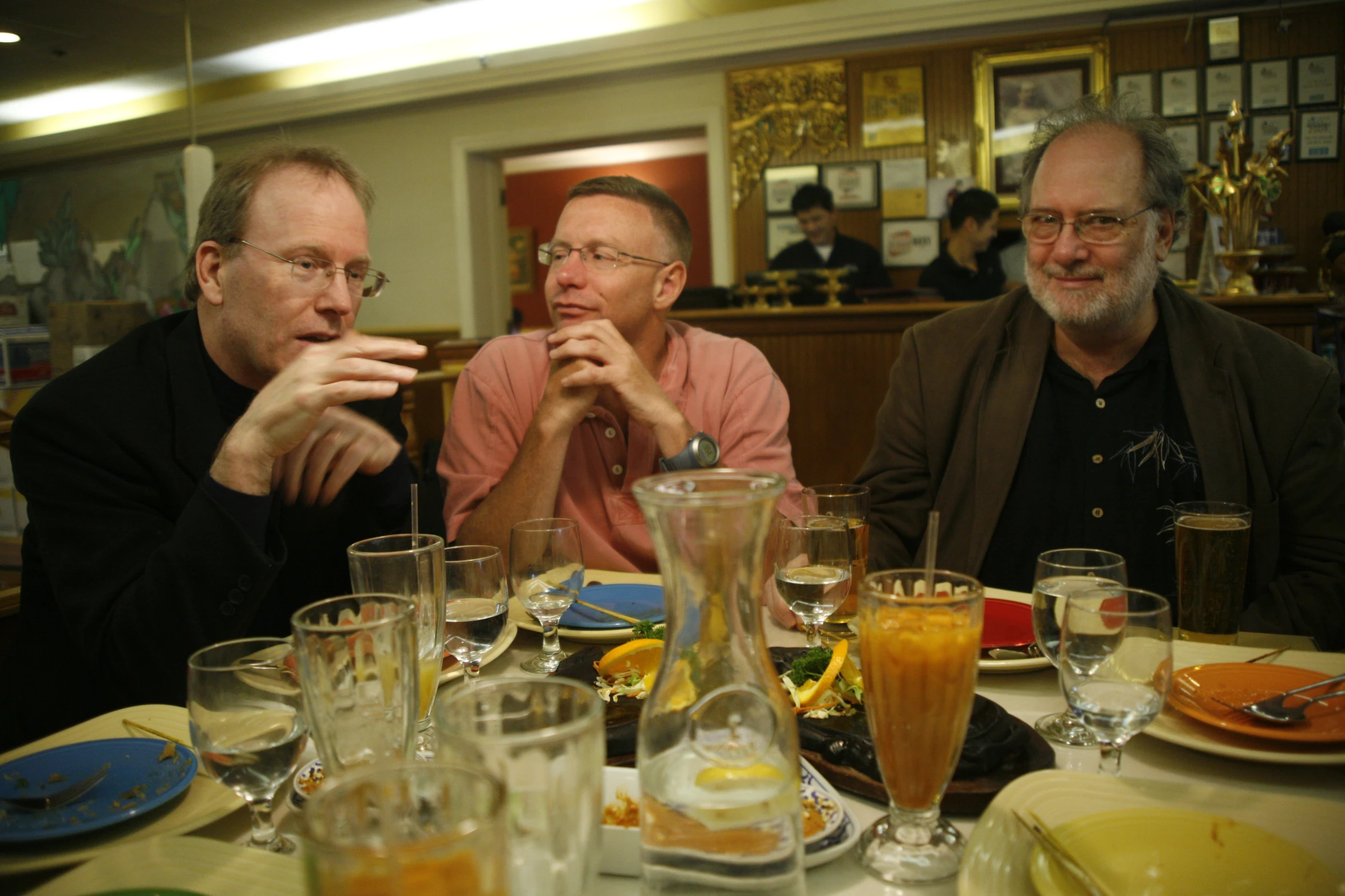 two men sitting at a table with several drinks in glasses