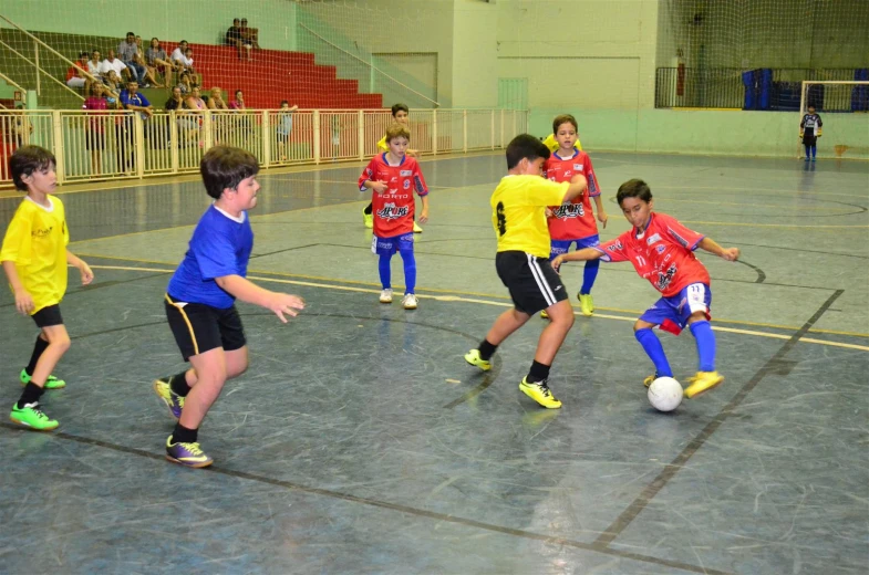 children in a gym playing soccer on a ball