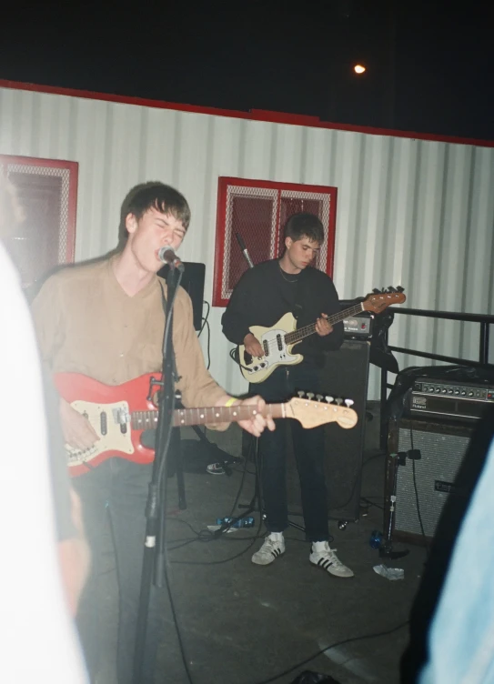 two young men standing next to each other on stage with guitars