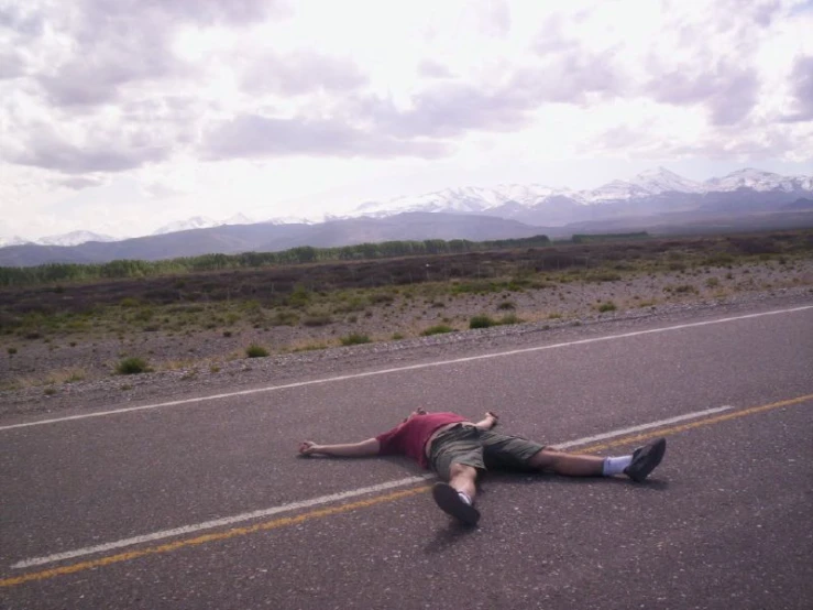 a man lies in the middle of a road